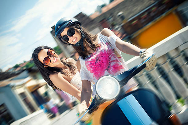 Happy young womens riding scooter enjoy summer vacation