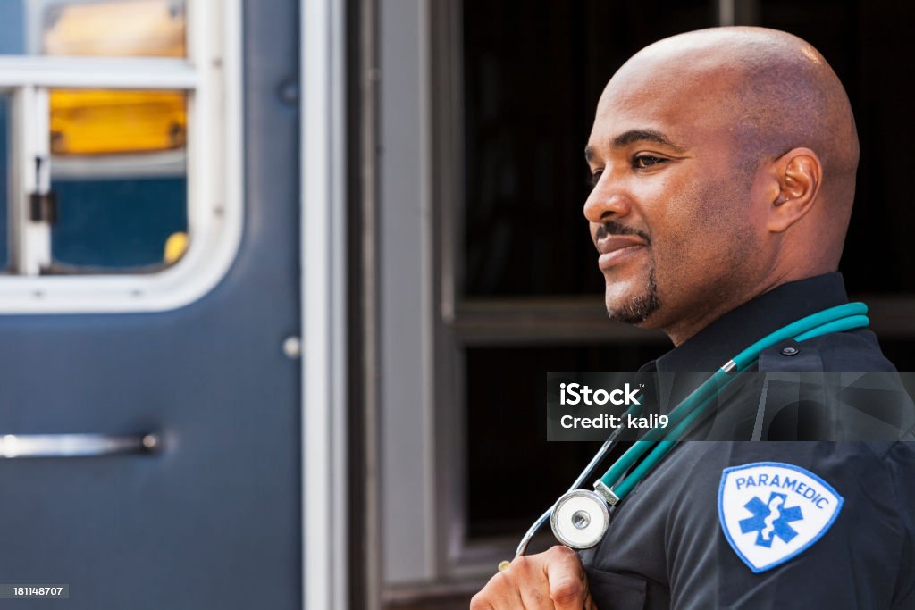 Paramedic standing by ambulance Close up of male paramedic (40s, mixed race African American and Hispanic) standing at rear door of ambulance. Paramedic Stock Photo