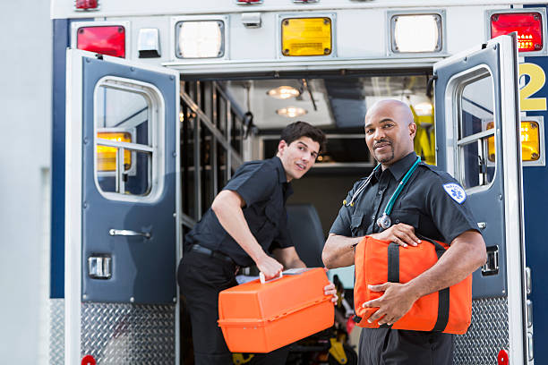 Paramedics at back of ambulance Multi-ethnic paramedics loading equipment into back of ambulance.  Focus on man on right (40s mixed race, Black and Hispanic). paramedic stock pictures, royalty-free photos & images