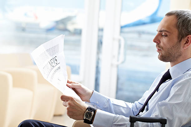 Businessman with newspaper Businessman reading latest news newspaper airport reading business person stock pictures, royalty-free photos & images