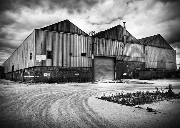 Intentional moody black and white image of a derelict fabricated building on an industrial estate, highlighting urban decay.