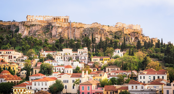 Traditional buildings in the Anafiotika area of Athens in the foreground, with the cliff leading up to the Parthenon on the Acropolis on the horizon.