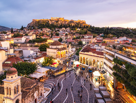 A high angle cityscape of Athens, with Monastiraki Square in the foreground, and the Parthenon on the Acropolis on the horizon.