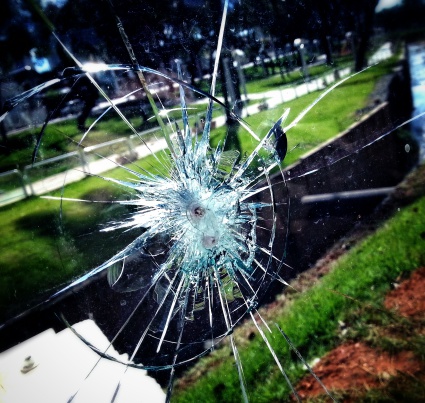 Photo of shattered glass, with a beautiful park on background.