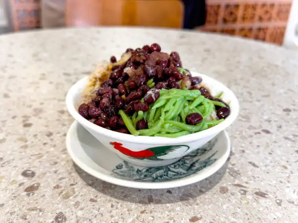 Photo of Malaysia traditional local dessert called Cendol. Cendol is made from crushed ice cubes, sugar gula Melaka, red beans, pandan green rice flour jelly on top.