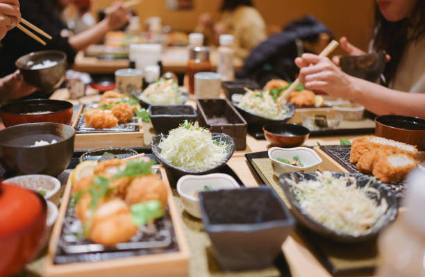 gruppe von freunden isst traditionelles japanisches essen tonkatsu set mit einer auswahl an japanischem essen - osaka prefecture stock-fotos und bilder