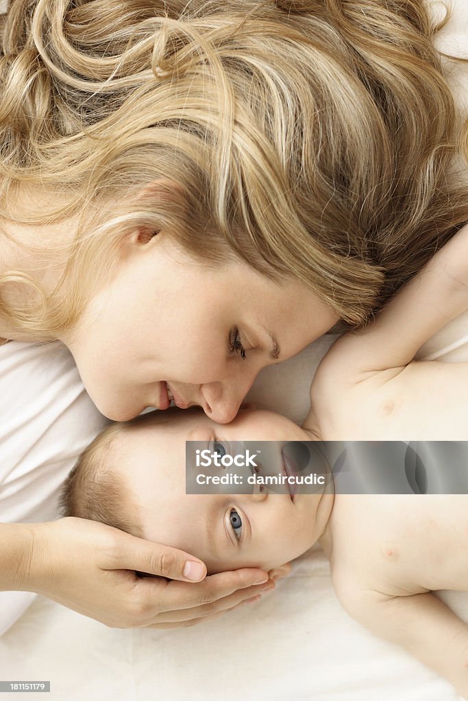 Madre y bebé relaja en la cama - Foto de stock de 20 a 29 años libre de derechos