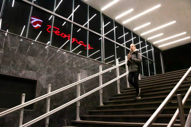 nastoletnia dziewczyna na schodach metra, z odbijającymi się światłami wewnętrznymi i znakiem domu towarowego w belgradzie - cyrylica zdjęcia i obrazy z banku zdjęć