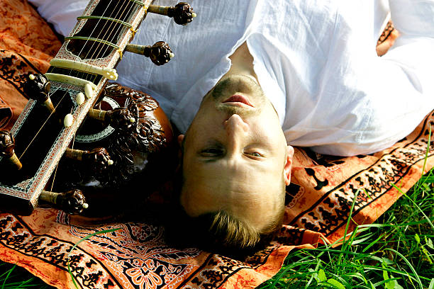 istock Young Man Lying on Ethnic Scarf Beside Sitar 181151943