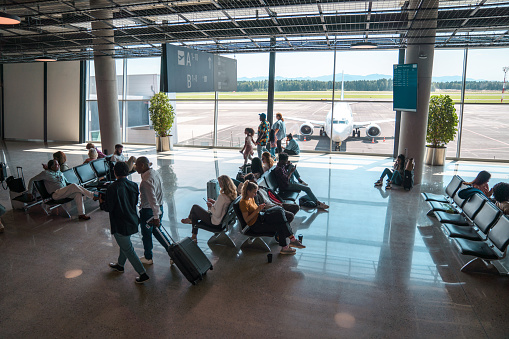 Long exposer people traveling through Logan Airport terminal before Christmas wearing face-mask.