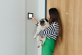 Woman with Dog Using Smart Home Devise at Her Modern Apartment