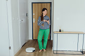 Man Using Robot Vacuum Cleaner at Her Modern Apartment