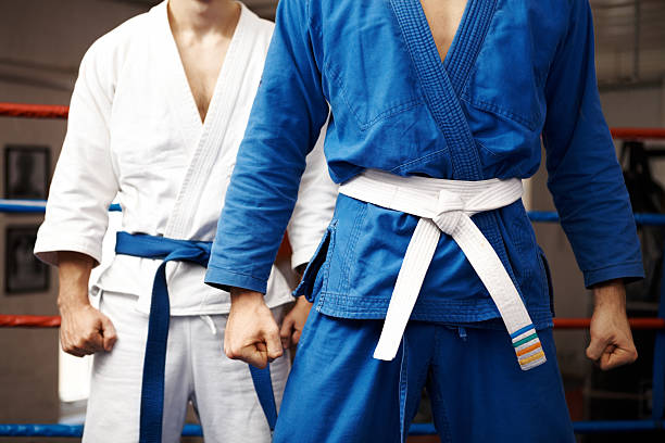Stand your ground Two judo fighters stand their ground with fists ready to fight - cropped kimino stock pictures, royalty-free photos & images