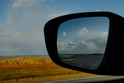 Russia. South of Western Siberia, Kemerovo region. View of the sunset cloudy sky through the side mirror of the car.