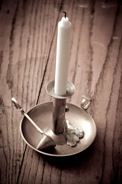 Brass candlestick with candles and candle snuffer placed on an old wooden table