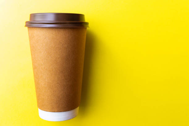 istock brown paper coffee cup on a yellow backgroud. Simple flat lay with copy space. Minimal concept. 1811563546