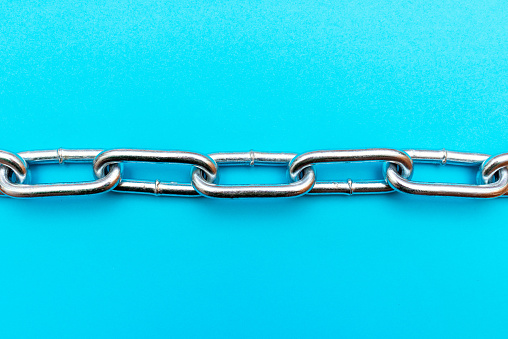 Top view Close-up metal chain lies on the blue background .Studio image.