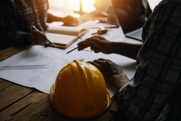 istock Two Specialists Inspect Commercial, Industrial Building Construction Site. Real Estate Project with Civil Engineer, Investor Use Laptop. In the Background Crane, Skyscraper Concrete Formwork Frames 1811581024