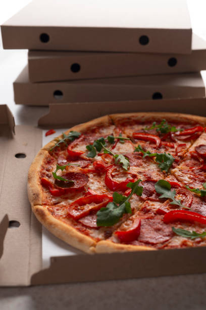 istock Large Pizza in open carton box on kitchen table closeup view 1811592075
