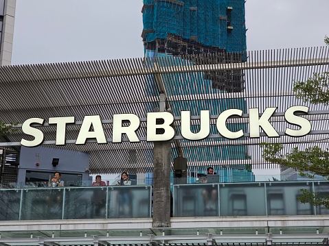 Starbucks Coffee Shop Famous Branches in Avenue of Stars at Tsim Sha Tsui in Hong Kong. Morning Or Afternoon View. Logo Starbucks Close-Up.