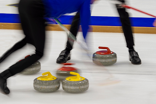 Sweepers working a fast moving stone during a curling match