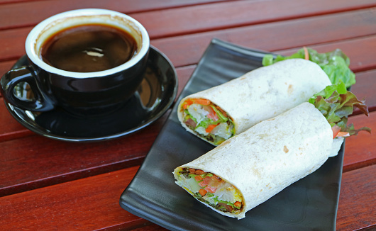 Plate of delectable chicken wrap sandwiches with a cup of coffee