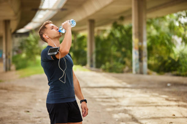 istock Male runner under bridge in the city drinking water 1811610143