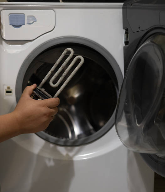 istock A man examines a heating element with scale against the background of a washing machine. The washing shirt does not work due to a burnt heating element. Washing machine breakdown concept. 1811617116