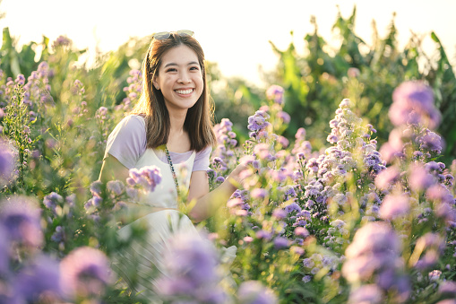 Portrait of asian Female excited happy when she sourrounding with wild flower chiang mai thailand