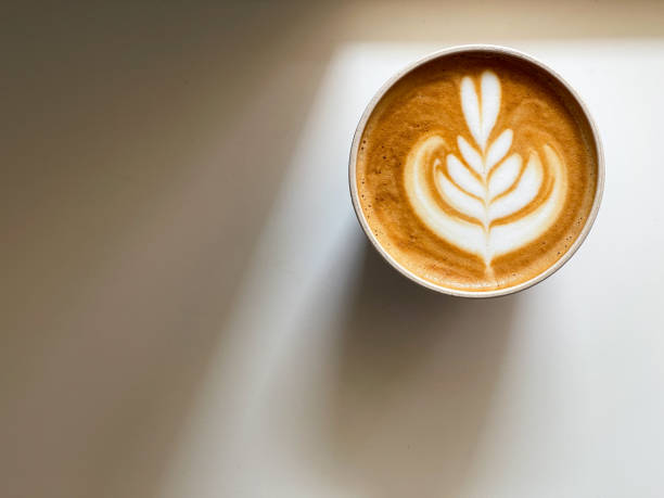 Coffee with heart shape latte art on white coffee table