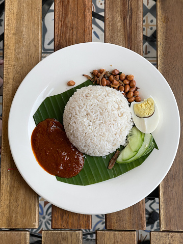 Nasi lemak - Malaysian coconut milk rice, served with egg, sambal, fried crispy anchovies, toasted peanuts and cucumber