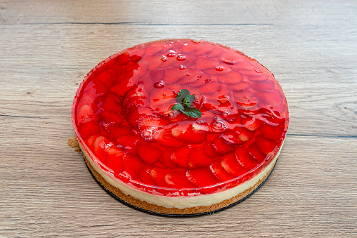 Sponge cake with custard cream and strawberries covered with jelly on top.