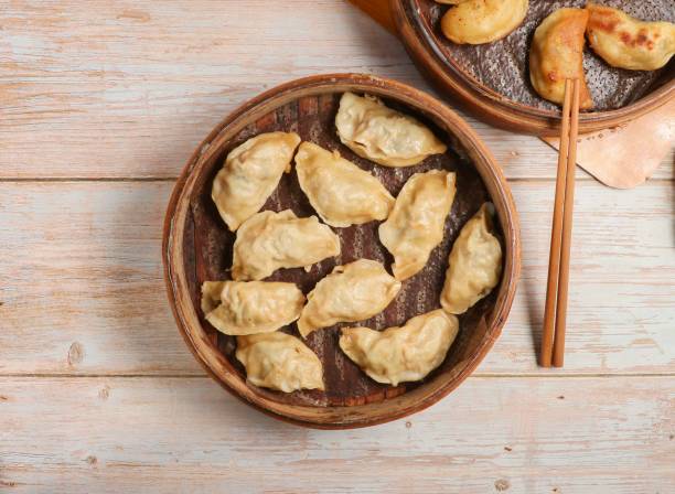 istock Handmade steamed dumplings and fried dumpling or momo served in wooden dish with chopsticks isolated on table top view Japanese food 1811668593