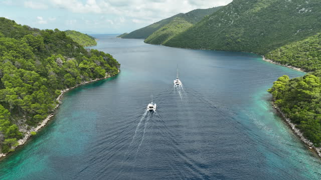 Drone panning shot of two catamaran's sailing in a bay at Mljet Island on a sunny day.