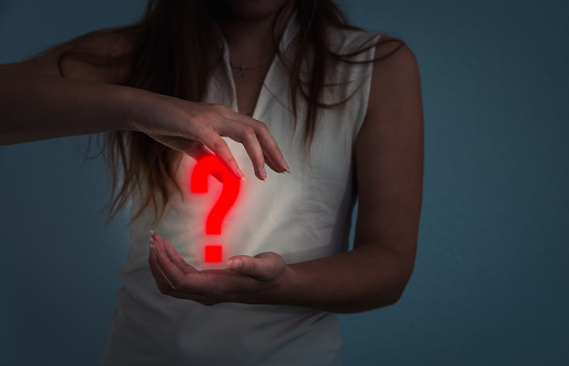 woman holding a red glowing question mark ,concept of question and answer or frequently asked questions .