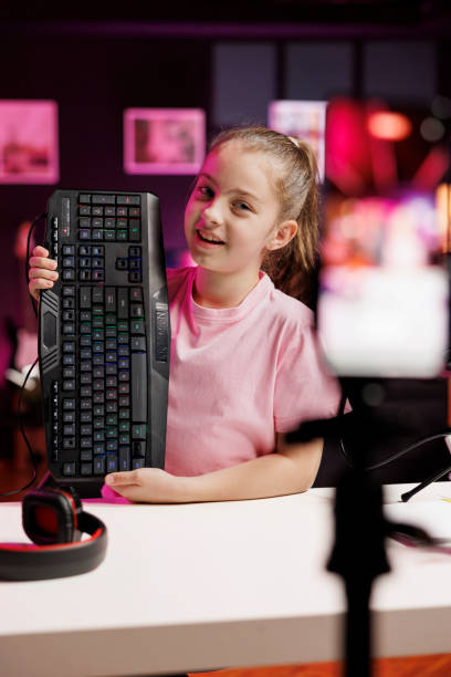 petite fille présentant un périphérique d’ordinateur éclairé rvb au public - computer peripheral photos photos et images de collection