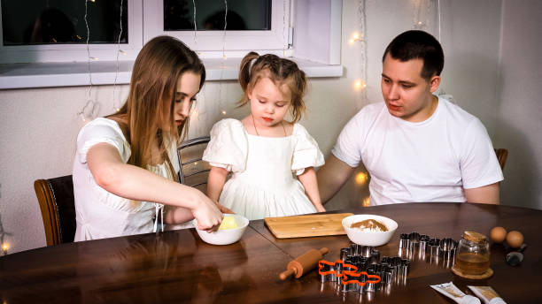 a family of three makes cookies together. - two parent family indoors home interior domestic kitchen imagens e fotografias de stock
