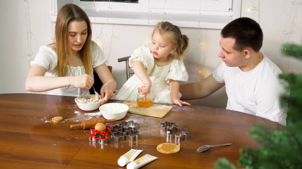 a little girl enjoys some honey from a jar - two parent family indoors home interior domestic kitchen imagens e fotografias de stock