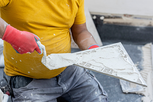 detail of a worker cementing a ceramic tile