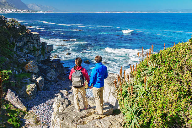 Couple hiking in South Africa,  looking at beautiful ocean view Happy couple looking at beautiful ocean view in Hermanus, romantic vacation in South Africa hermanus stock pictures, royalty-free photos & images
