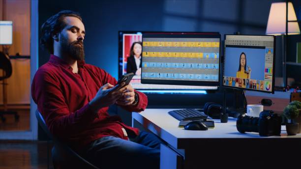 istock Photo editor taking break after doing color grading on images, relaxing by using smartphone 1811716900