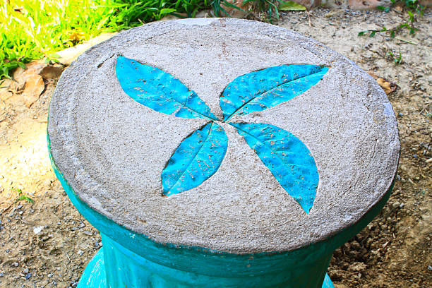 A weathered stone sphere centerpiece surrounded by a vibrant display of colorful flowering cabbages in a garden setting.