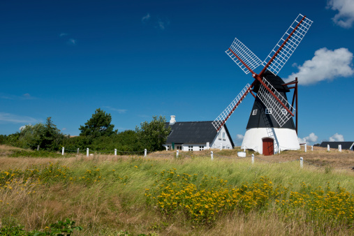 Characteristic landscape on the island of Öland (Sweden) with wooden mill and a farmhouse painted red and white