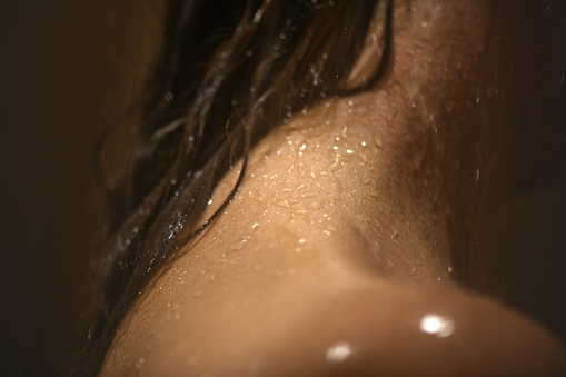 Close-up of a woman taking shower in a bathroom.