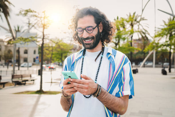 istock Young adult man using his smartphone messaging and chatting while walking through the street, enjoying his free time. Smiling guy holding a cellphone, texting a post or browsing on social media app. 1811758829
