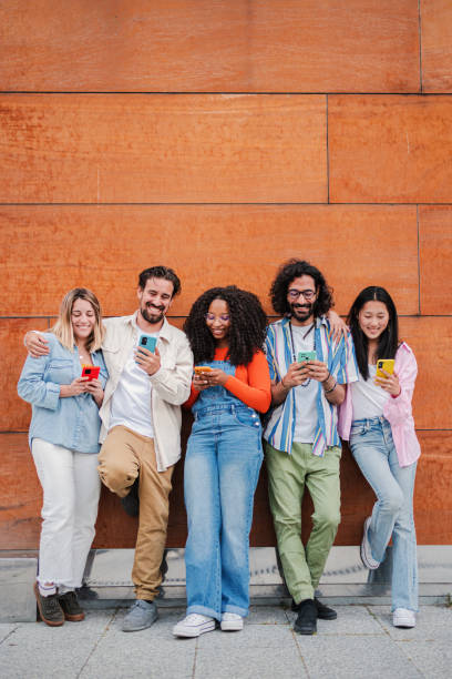 istock Vertical portrait with copy space. Group of happy multiethnic friends using a smartphone to share on social media. Young people addicted to cellphone app. Cool men and women watching a mobile phone 1811770265