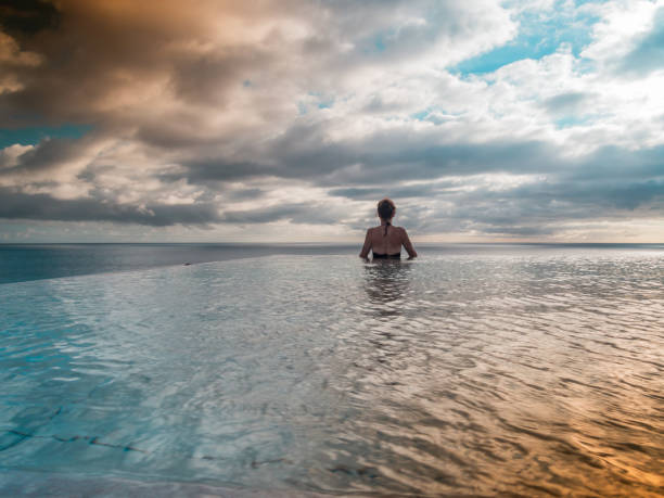 istock Back view of a woman standing in an infinity pool 1811789379