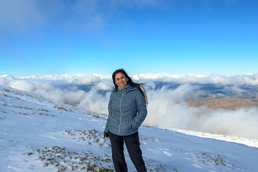 istock portrait of latina woman in the snow above the clouds, 1811790512