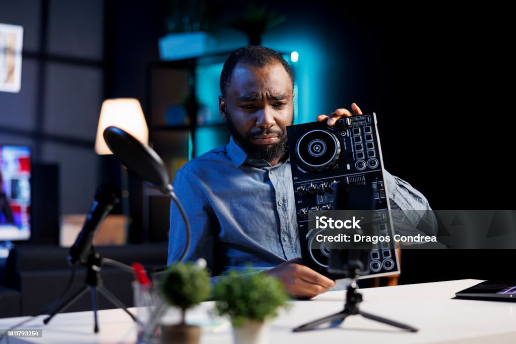 Reviewer unhappy with DJ controller Influencer reviewing DJ controller device, expressing dissatisfaction with subpar quality. Content creator shooting video for online channel, displeased with sound mixer gear performance Adults Only Stock Photo