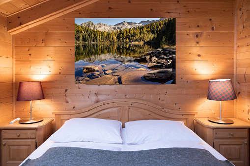 A cosy bed in a hotel room decorated with wooden materials and a picturesque wall photo. High quality photo